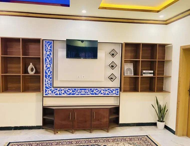 TV lounge with shelving and a blue tile wall